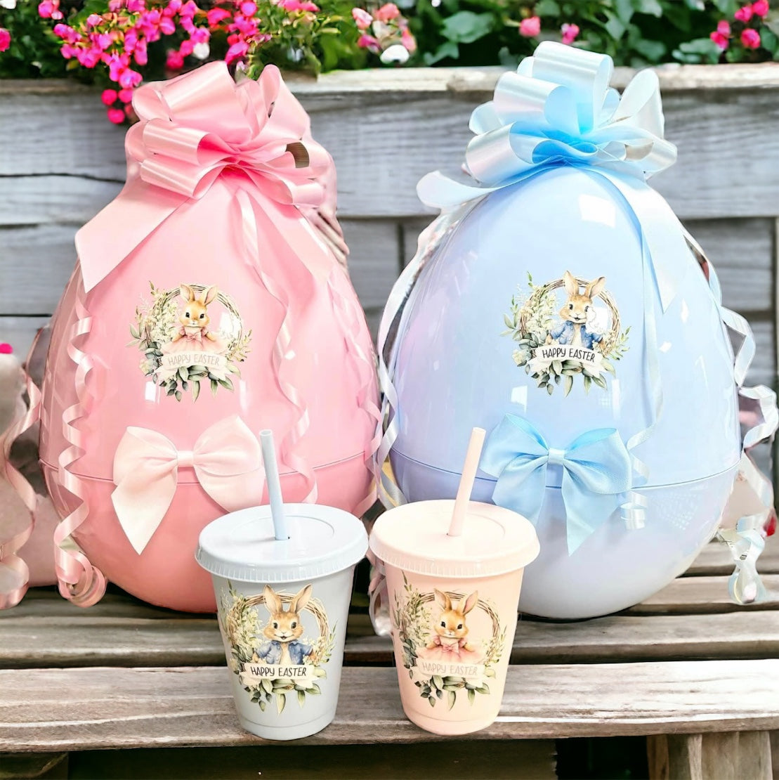 Two extra large plastic Easter eggs in pink and blue, with decorative elements and personalized sections, displayed on a wooden surface with a floral patterned backdrop.