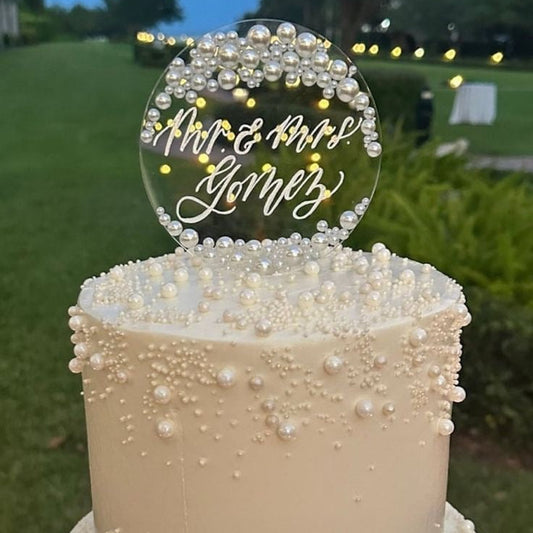 Two-tiered wedding cake with decorative topper in an outdoor setting