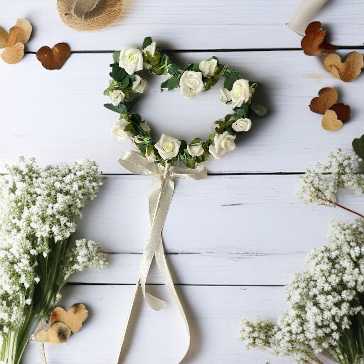 Heart-shaped arrangement of white flowers with a wooden spoon on a light wooden surface.