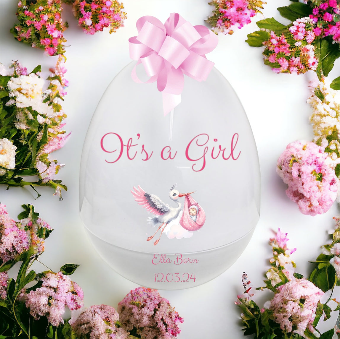 Decorative item with 'It's a Girl' text, stork, and baby footprint, surrounded by pink flowers on a white background.
